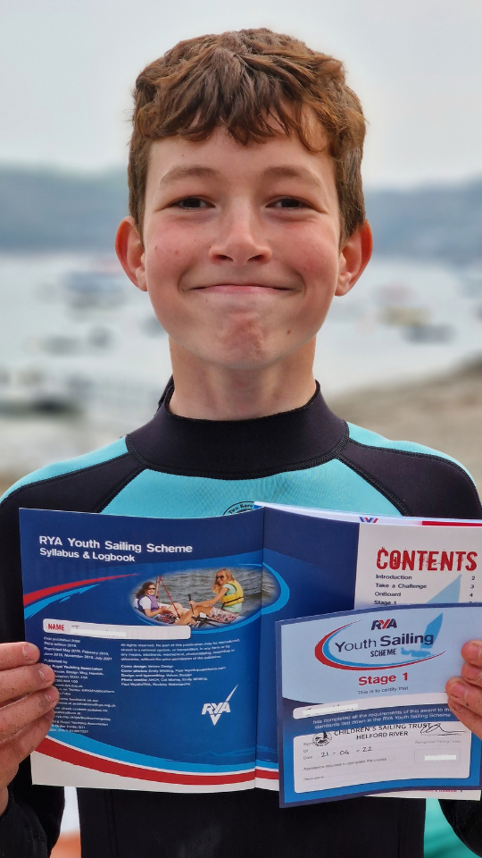 Happy child receiving Stage 1 Sailing certificate from Children's Sailing Trust
